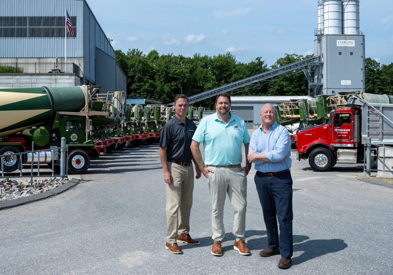 A photo of Rob Morton, Jeff Rawson, and Shawn McNerney at a ready-mix concrete company. There are concrete trucks in the background.