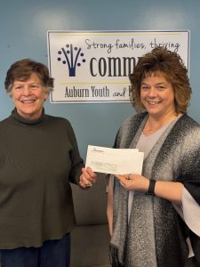 Two women holding a check donation for the Auburn Youth and Family Services Food pantry. 