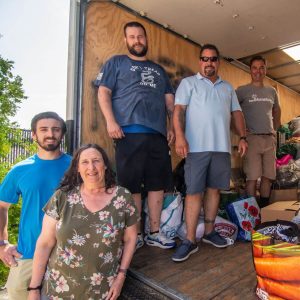 Bank employees standing in a box truck full of clothing donations.