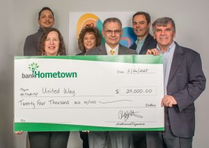 A group holds up a large check donation to the United Way